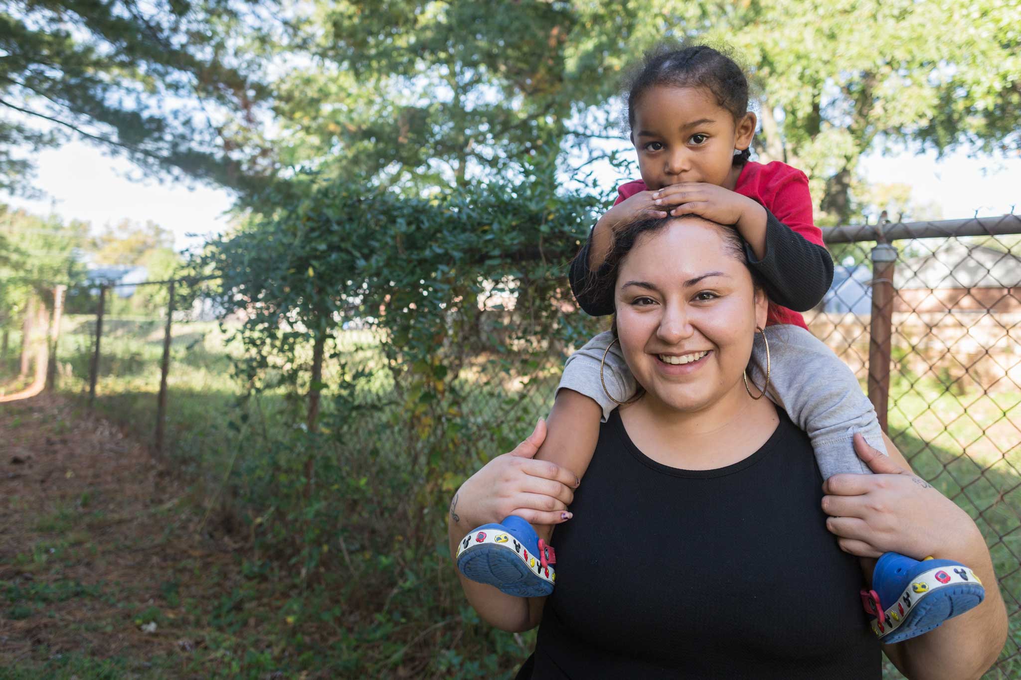 Photo of Angela with child on her shoulders.