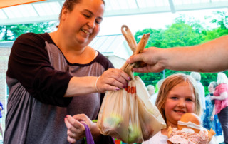 Woman and child picking up a bag of apples at a VeggieVanGo