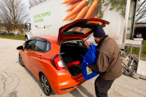 Photo of a man loading bags of food into a car at a VeggieVanGo event.