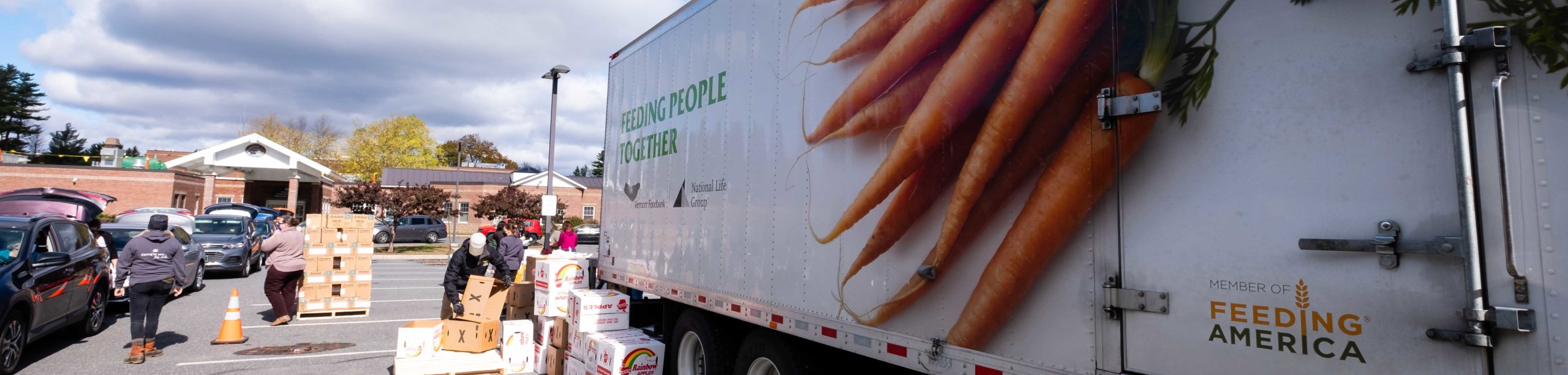 Photo of a VT Foodbank truck at a VVG site, volunteers are loading food into vehicles.