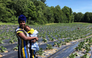 Photo of Janine and one of her children in a field of African eggplant.