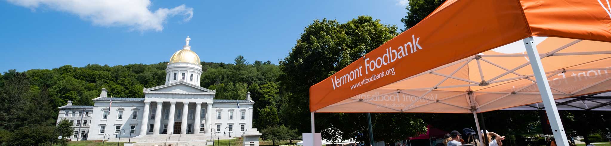 Photo of the Vermont State House and a Vermont Foodbank tent in the foreground.