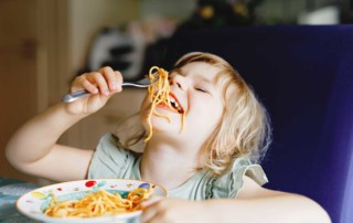 Photo of a child eating pasta -- find out if you're eligible for 3SquaresVT by contacting the Vermont Foodbank.