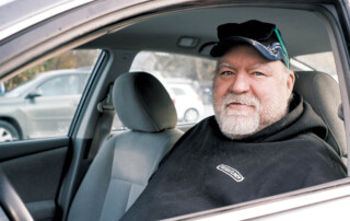 Photo of Joe, who's been speaking up to support neighbors facing hunger, sitting in his car.