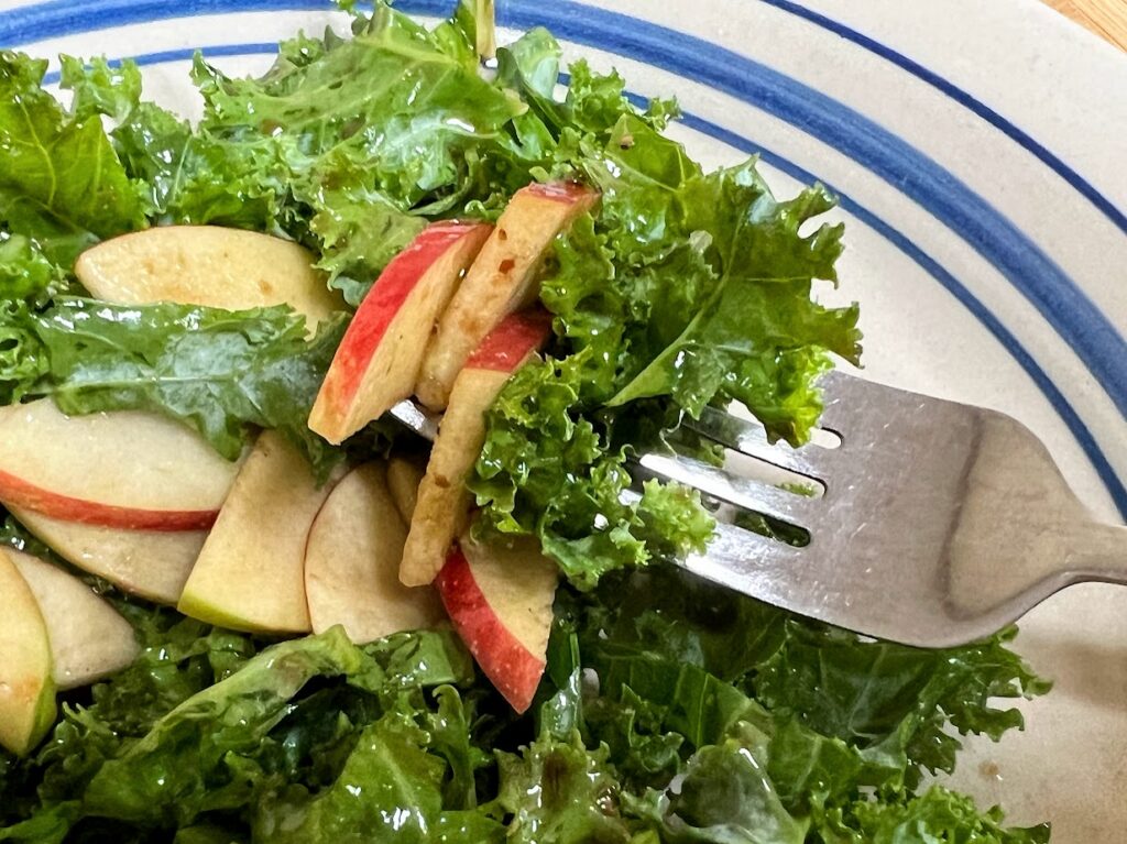 Kale and apple salad on a plate with a fork