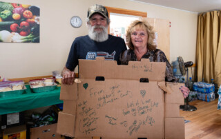 Photo of volunteers at Neighbors in Action holding up a sign with messages of gratitude from community members.