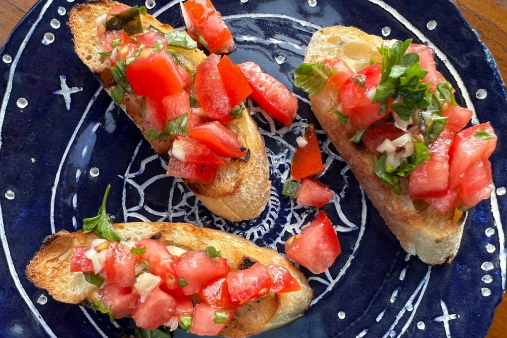 Close up of 3 pieces of Tomato Bruschetta on blue plate