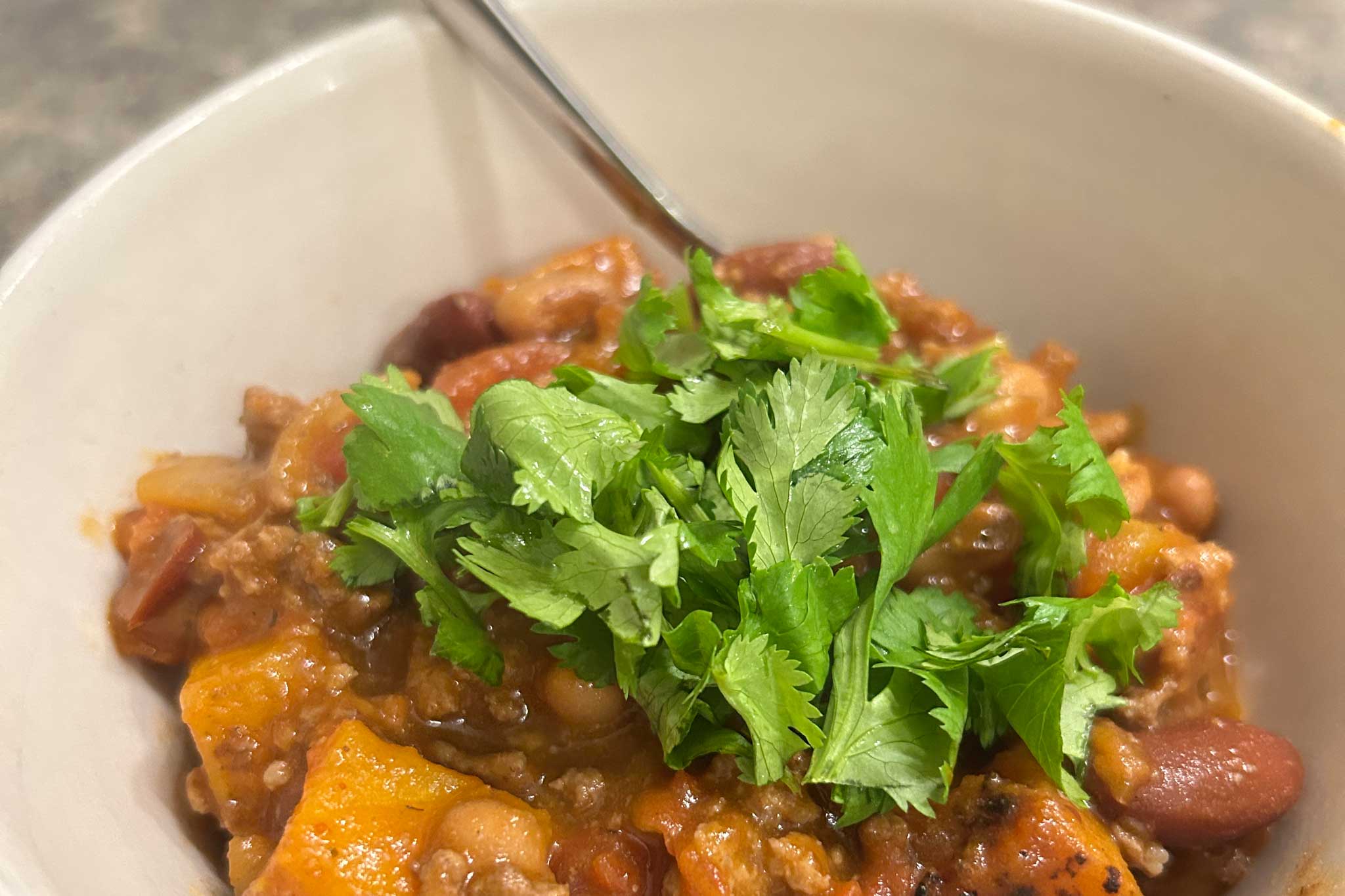 Chili in a bowl with cilantro on top.