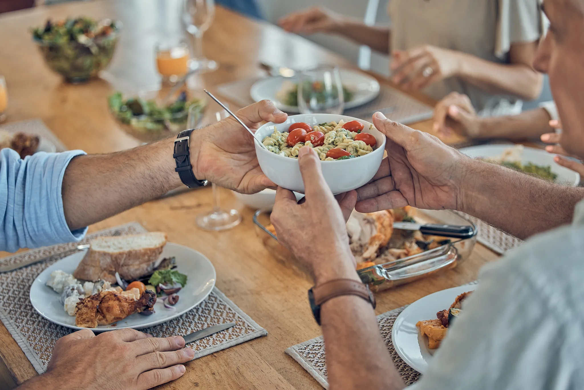 Photo of hands passing food at a table.